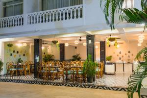 a restaurant with tables and chairs and a balcony at La Vaiencia Beach Resort, Morjim Beach in Morjim