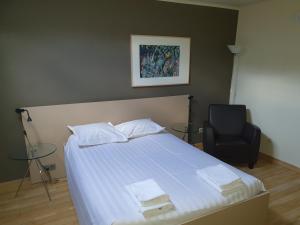 1 dormitorio con 1 cama y 1 silla negra en Carré en Lommel