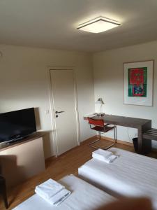 a room with two beds and a desk and a television at Carré in Lommel