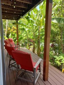 two red chairs sitting on a wooden deck at Tropical Retreat on Magnetic Island in Picnic Bay