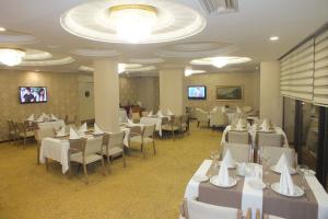 uma sala de jantar com mesas e cadeiras brancas em Park Royal em Adana