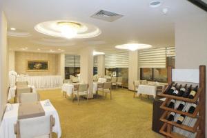 a restaurant with white tables and chairs and wine bottles at Park Royal in Adana