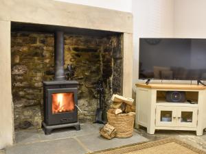 a stone fireplace with a television and a stove at Meadow View Cottage in Stanhope