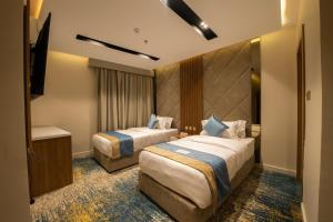 a hotel room with two beds and a television at Grand day in Al Hofuf