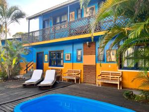 un edificio azul y amarillo con sillas y una piscina en Pousada La Croix, en Florianópolis