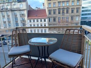 two chairs and a table on a balcony with buildings at Balcony Apartment, 5 min Walk to First District in Vienna