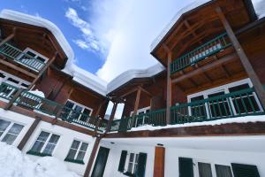a large wooden building with snow on the ground at Därfli Appartements in Sankt Gallenkirch