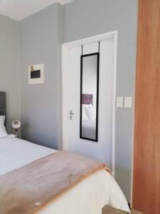 a white bedroom with a bed and a mirror at Cosy apartment with secure parking in Johannesburg