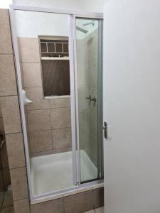 um chuveiro com uma porta de vidro na casa de banho em Cosy apartment with secure parking em Joanesburgo