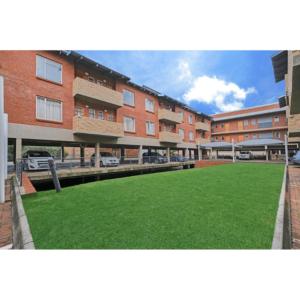 um grande edifício com um relvado verde em frente em Cosy apartment with secure parking em Joanesburgo