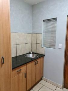 una pequeña cocina con fregadero y ventana en Cosy apartment with secure parking, en Johannesburgo