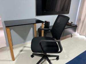 un bureau noir avec une chaise et une télévision dans l'établissement Piemax Praia Grande - 100m PRAIA do BOQUEIRÃO e CENTRO - Vista MAR - Varanda GOURMET com CHURRASQUEIRA privativa - AR CONDICIONADO em todos os ambientes - Wi-Fi 600 Mbps - HOME OFFICE- Vaga de Garagem - Acomoda até 6 pessoas, à Praia Grande