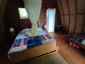 a bedroom with a bed with two blue shoes on it at Wajonata Sumba in Baing