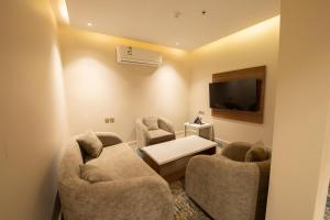 een woonkamer met 2 stoelen en een flatscreen-tv bij Grand day in Al Hofuf