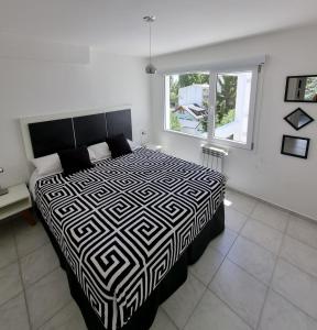 a bedroom with a black and white bed and a window at Bariloche Modern Apartment Belgrano in San Carlos de Bariloche
