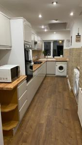 a kitchen with white cabinets and a microwave at Large 4 Bedrooms House in Coventry for Contractors in Whitley