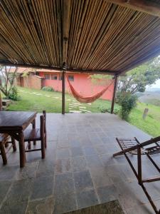 um pátio com uma rede de descanso, uma mesa e cadeiras em Pousada Mirante Serra Verde em Carrancas