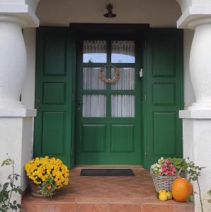 a green door with two vases of flowers in front at Deák Vendégház Dörgicse in Dörgicse
