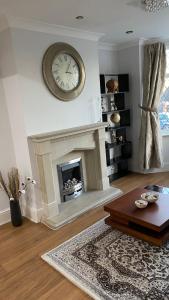 a living room with a fireplace with a clock on the wall at Large 4 Bedrooms House in Coventry for Contractors in Whitley