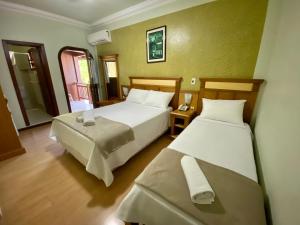 a hotel room with two beds and a window at Pousada Gramado in Gramado