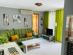 a living room with a green couch and a tv at Apartmán - MARIS in Puerto de Mogán