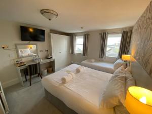 Un dormitorio con una gran cama blanca y un escritorio. en Alexandra Hotel, en Weymouth