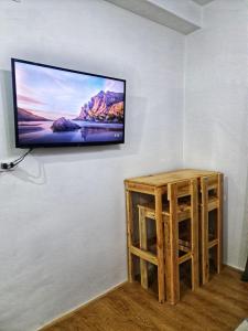een flatscreen-tv aan een muur met een houten kruk bij Mesatierra Garden Residences in Davao City