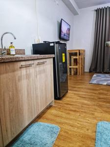 een keuken met een zwarte koelkast en een houten vloer bij Mesatierra Garden Residences in Davao City