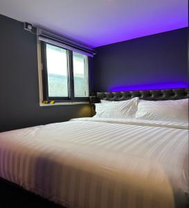 1 dormitorio con cama blanca y techo púrpura en HOTEL JJH - newly opened near BUGIS en Singapur