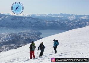 three people skiing down a snow covered slope with a clock at Turismo y Cabañas Dragon de La Patagonia in Cochrane