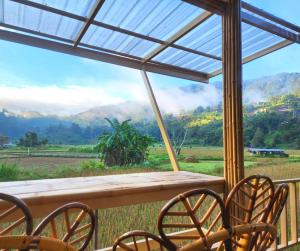 a table and chairs on a porch with a view at สะปัน กลางนา คาเฟ่ Sapan Klang Na Cafe in Ban Huai Ti