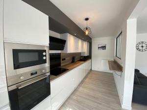 cocina con armarios blancos y TV en la pared en Magnifique appartement à deux pas du centre ville!, en Quimper