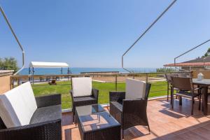 a patio with chairs and tables and a view of the ocean at Venetico Beachfront Apartments & Suites - 2 Bedroom Sea View Suite in Argasi