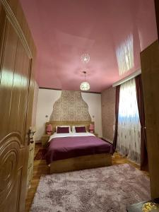 a bedroom with a large bed with a purple ceiling at Guest House Elguja Qushashvili in Stepantsminda