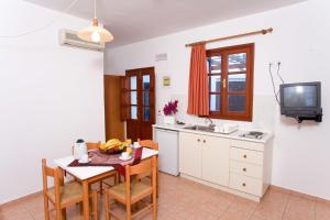 a kitchen with a table and chairs and a tv at Anastasia Studios Lindos in Líndos