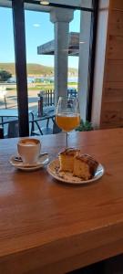 un vaso de zumo de naranja y un trozo de pastel en una mesa en APARTAMENTOS LAS OLAS BY PANTIN, en Valdoviño