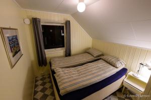 a small bed in a small room with a window at Cozy house on Sommarøy in Sommarøy