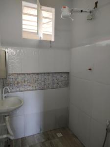 een witte badkamer met een wastafel en een raam bij Kitnet em Cabo Frio 02 in Cabo Frio