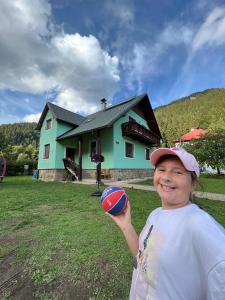 a young boy holding a ball in front of a house at VILLA LÚČKY in Lúčky