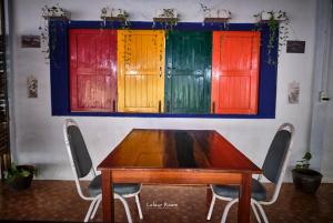 a wooden table with chairs in a room with colorful doors at Hill Station Hostel at Chor Chaba in Ko Kood