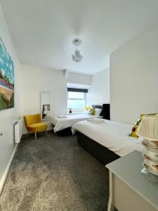 a bedroom with two beds and a yellow chair at Angel Lane Alnwick Apartment in Alnwick