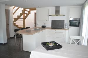 a kitchen with white cabinets and a sink and a table at Sous le Saule Holiday Home in Heyd