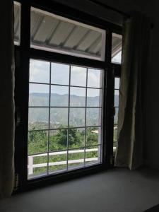 ein Fenster in einem Zimmer mit Blick auf ein Feld in der Unterkunft SKY TOUCH COTTAGES AND STAYS UNIT 2 in Mukteswar + 2 Fotos