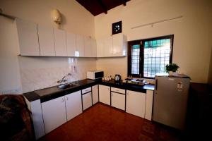 eine Küche mit weißen Schränken und einem Edelstahlkühlschrank in der Unterkunft SKY TOUCH COTTAGES AND STAYS UNIT 2 in Mukteswar
