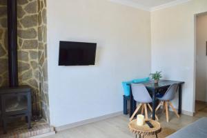 sala de estar con mesa y TV en la pared en Piso Al Lago - Appartment with Fabulous Lake Views en Zahara de la Sierra