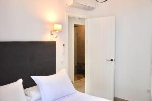 1 dormitorio con 1 cama con sábanas blancas y cabecero negro en Piso Al Lago - Appartment with Fabulous Lake Views en Zahara de la Sierra