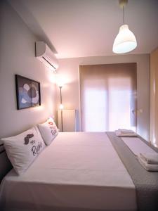 um quarto com uma grande cama branca e uma luz em Small Nest - Central Spot Apartments em Volos