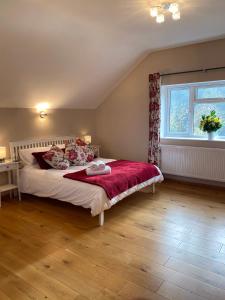 a bedroom with a large bed with a red blanket at The Loft at Pen Orchard in Winscombe