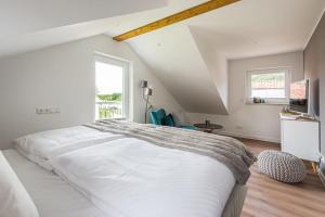 a white bedroom with a large bed and a window at 5 Sterne-Ferienhaus Eisvogel am See mit Sauna und Kamin in Krakow am See