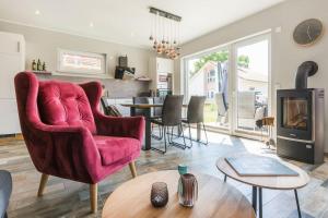 a living room with a red chair and a fireplace at 5 Sterne-Ferienhaus Eisvogel am See mit Sauna und Kamin in Krakow am See